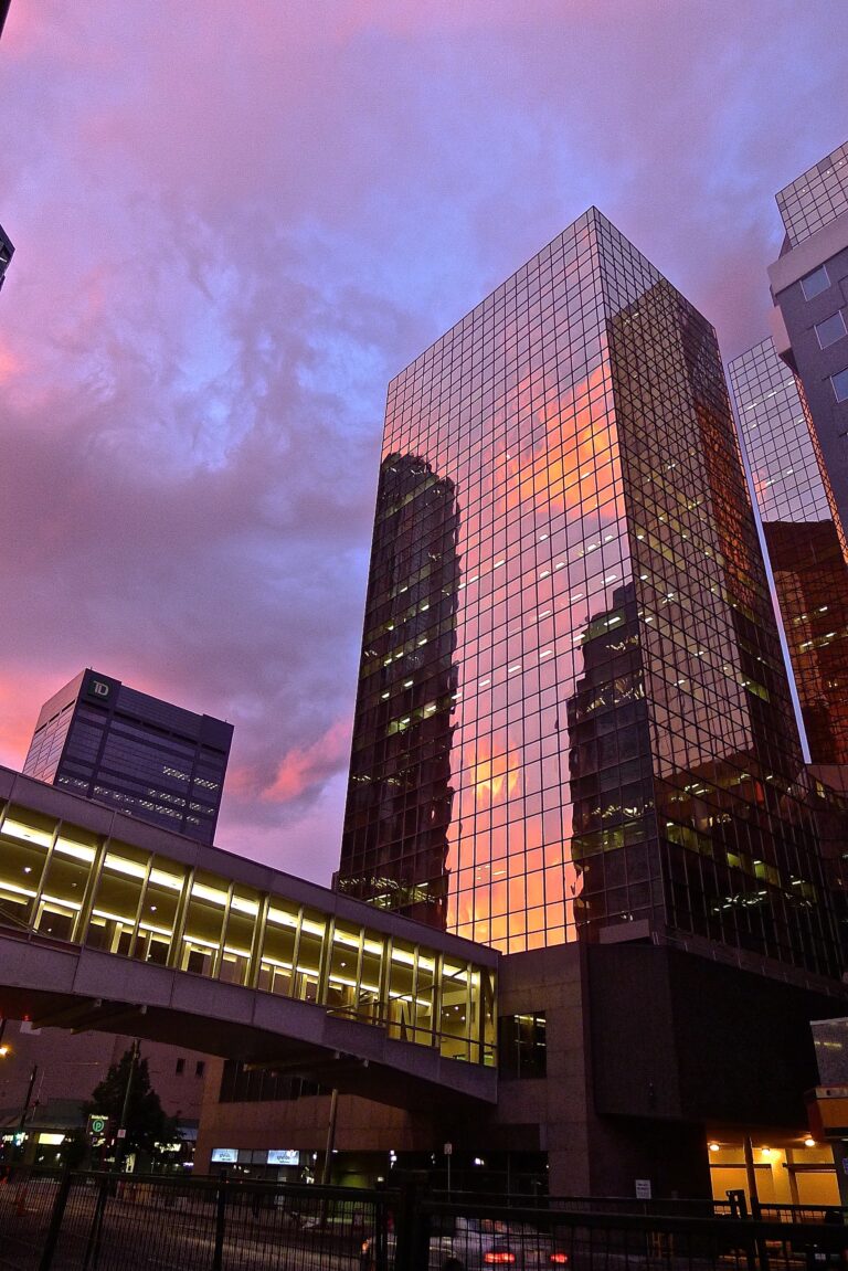 Gratte ciel vitré ultramoderne réfléchissant un coucher de soleil rouge et violet